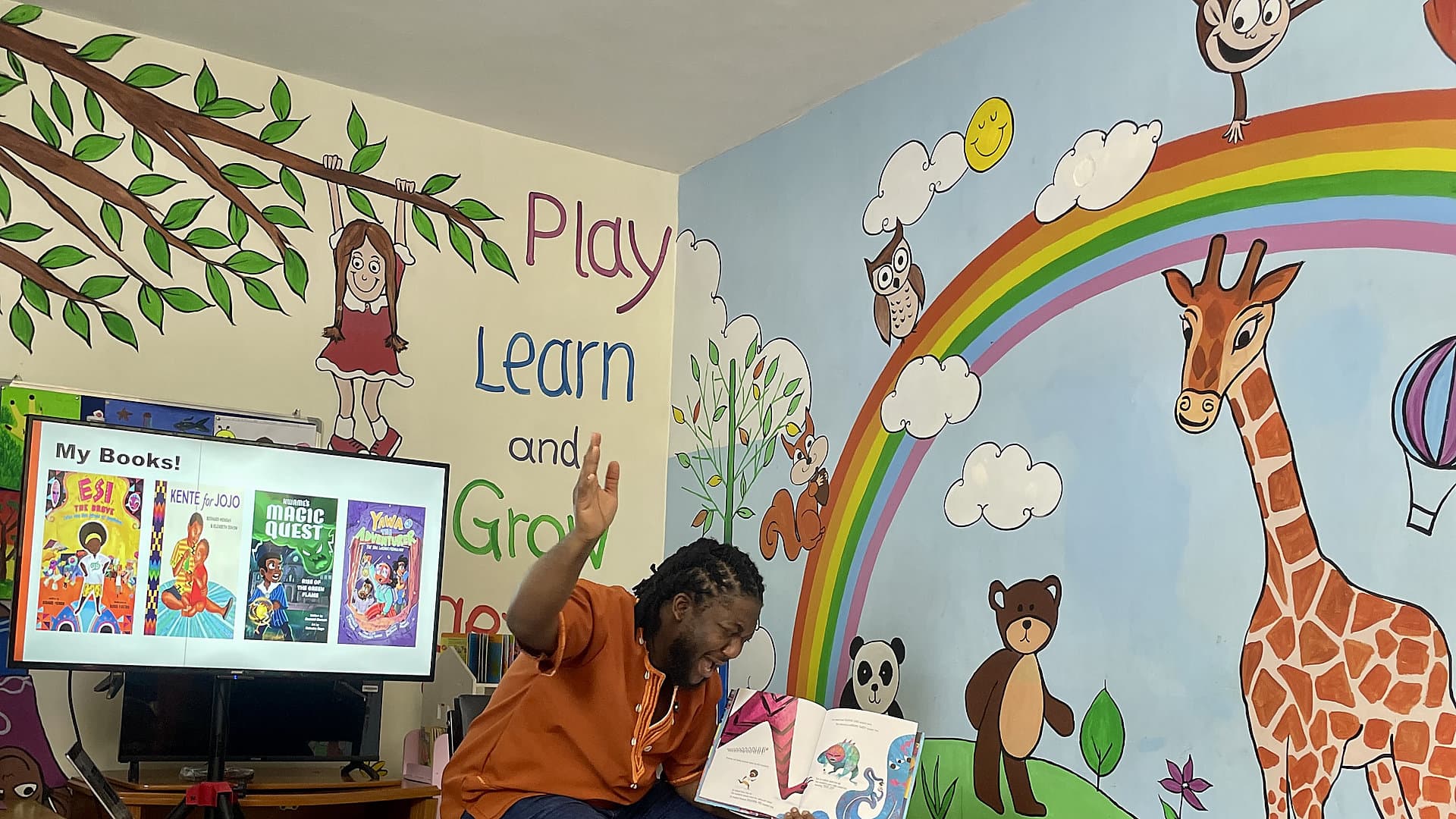 Bernard K. Mensah reading animatedly to a group of primary school children